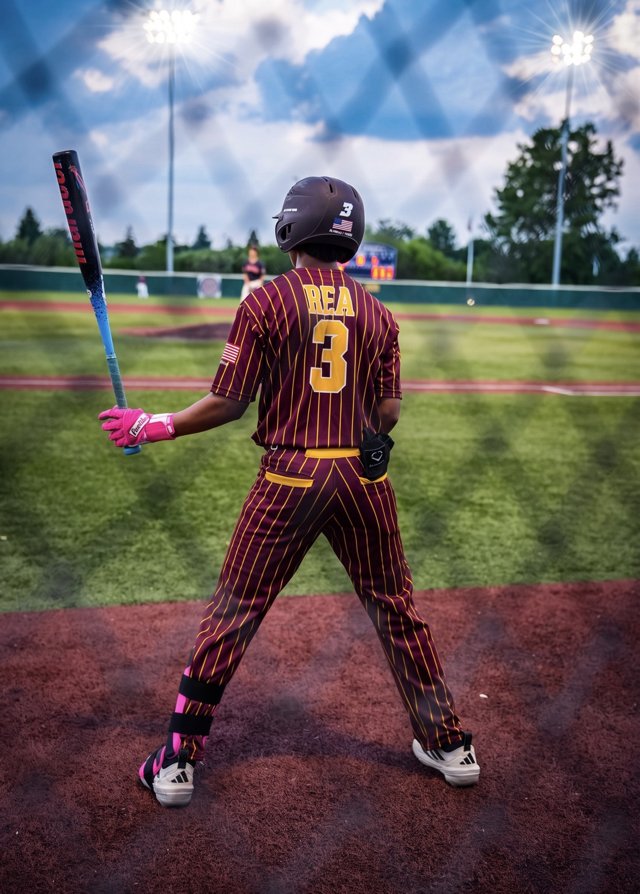 Baseball player warming up with a bat beside the field